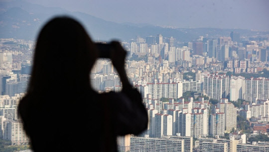 한 시민이 서울 영등포구 63스퀘어에서 아파트 밀집 지역을 촬영하고 있다. <연합뉴스>